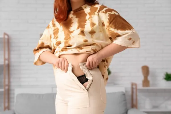 Image of woman trying to do her trousers up after pregnancy weight gain Stowmarket